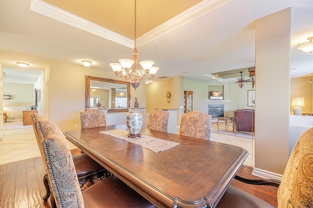 dining room with a tray ceiling, light hardwood / wood-style floors, ceiling fan with notable chandelier, and ornamental molding