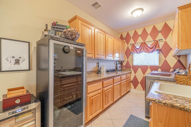 kitchen with stone counters, separate washer and dryer, stainless steel refrigerator, and light tile patterned flooring