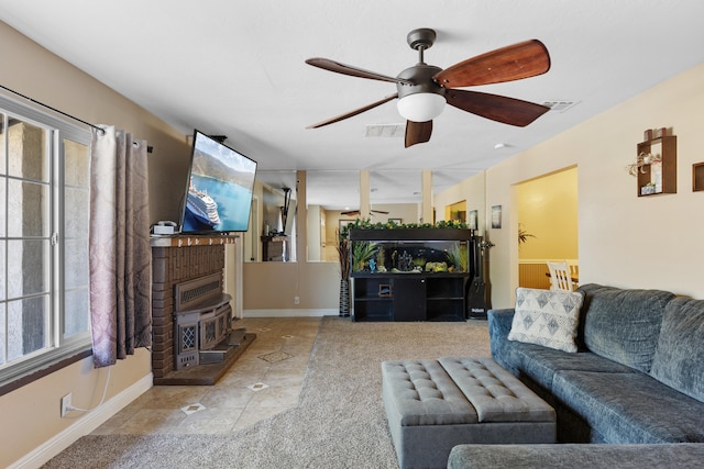 living room with a wealth of natural light, ceiling fan, light tile patterned floors, and a wood stove