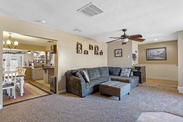 living room with a textured ceiling, light colored carpet, and ceiling fan with notable chandelier