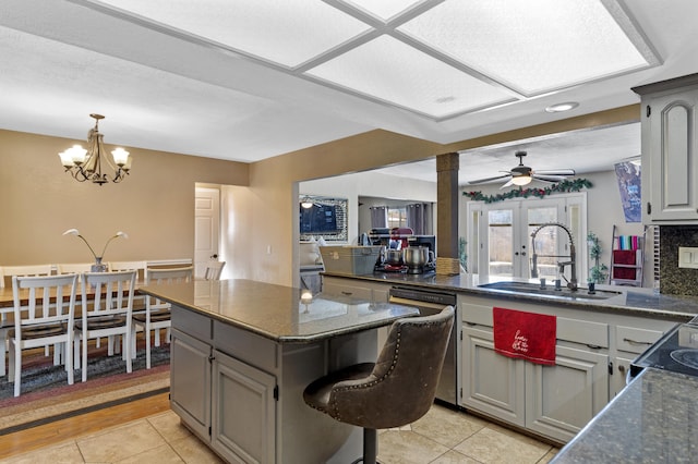 kitchen with gray cabinetry, ceiling fan with notable chandelier, sink, dishwasher, and a center island