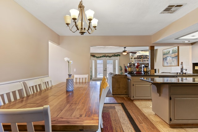 dining area featuring french doors, ceiling fan with notable chandelier, light hardwood / wood-style floors, and sink