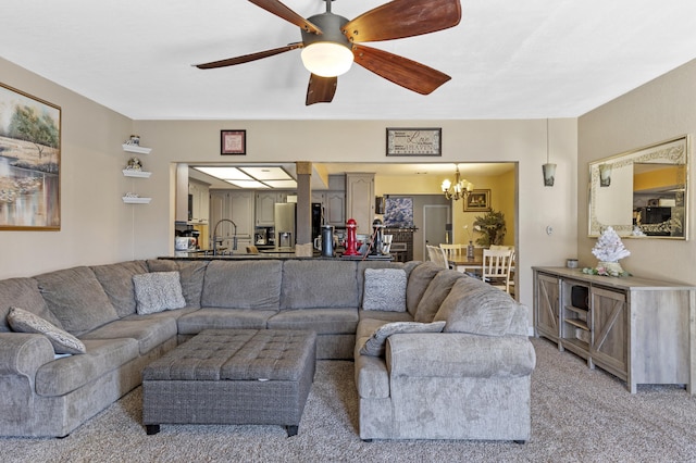 carpeted living room with sink and ceiling fan with notable chandelier