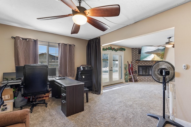 carpeted office space featuring a fireplace, french doors, and ceiling fan