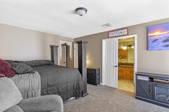 carpeted bedroom with sink and ensuite bath