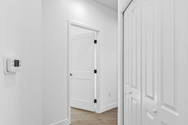 corridor featuring baseboards and light wood-type flooring