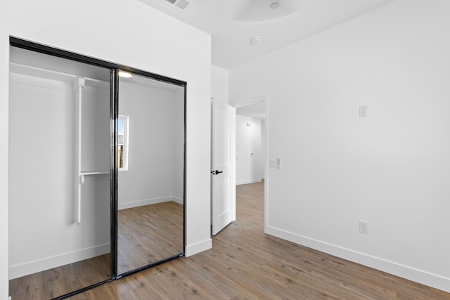 unfurnished bedroom with a closet, baseboards, and light wood-type flooring