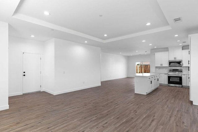 kitchen with stainless steel appliances, a raised ceiling, dark wood-type flooring, white cabinetry, and open floor plan