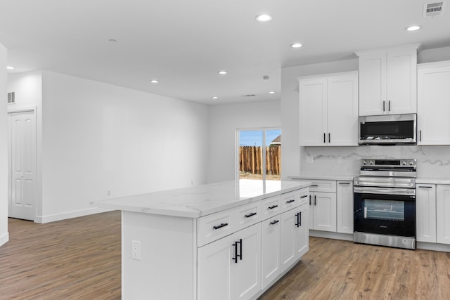 kitchen featuring backsplash, a kitchen island, appliances with stainless steel finishes, light wood-style flooring, and visible vents
