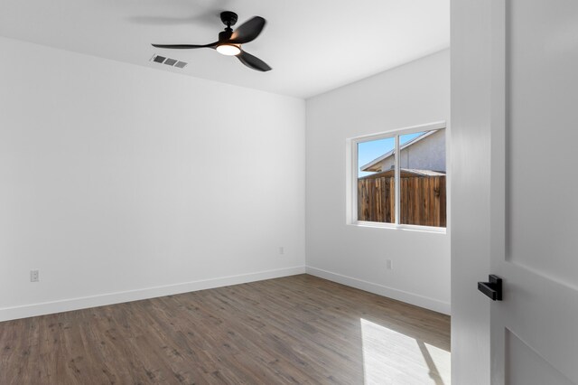 spare room with baseboards, visible vents, wood finished floors, and ceiling fan