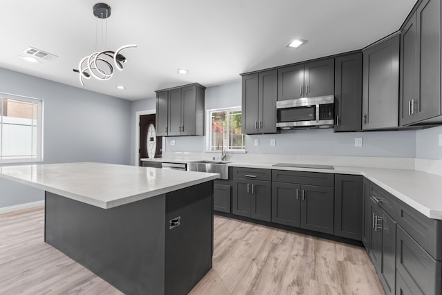 kitchen with black electric cooktop, sink, decorative light fixtures, a center island, and light hardwood / wood-style floors