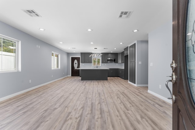 unfurnished living room with light hardwood / wood-style floors and a healthy amount of sunlight