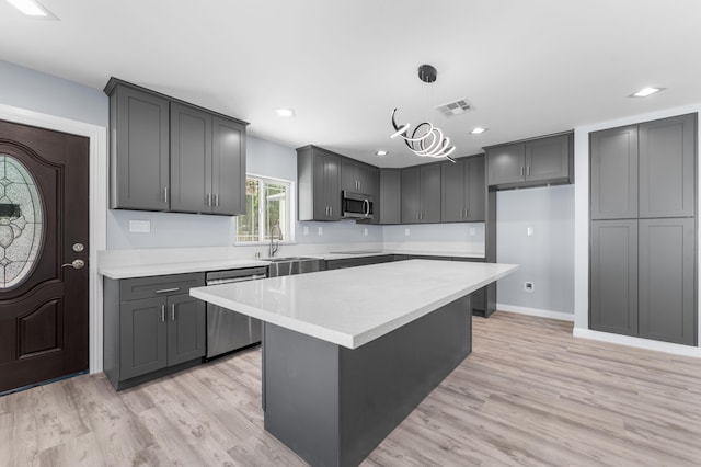 kitchen featuring gray cabinets, a kitchen island, appliances with stainless steel finishes, and pendant lighting