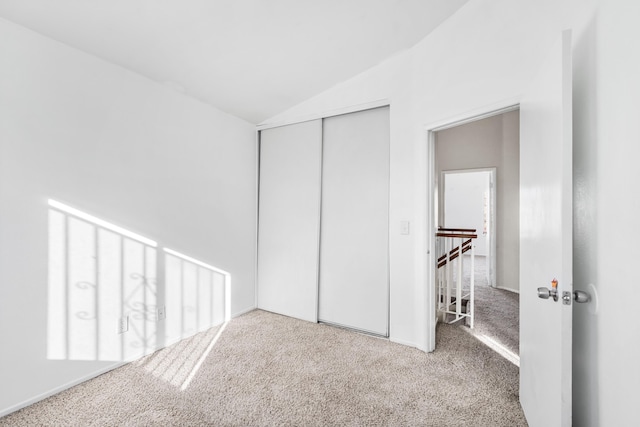 unfurnished bedroom featuring lofted ceiling, a closet, and carpet flooring