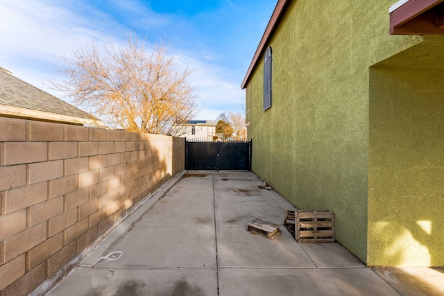 view of side of home featuring a patio area, fence, and stucco siding