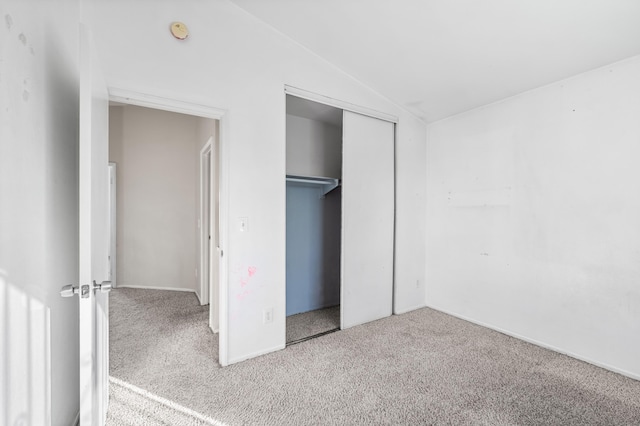 unfurnished bedroom featuring a closet, vaulted ceiling, and carpet flooring