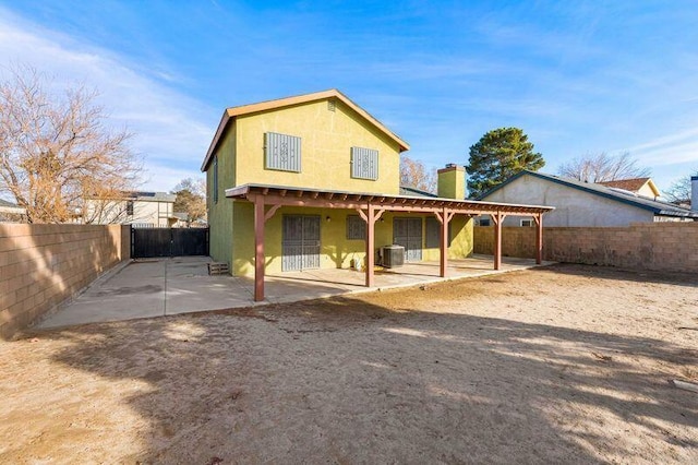 back of property with a patio, a fenced backyard, a chimney, central air condition unit, and stucco siding