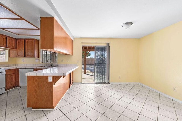 kitchen featuring a peninsula, white appliances, tile countertops, and brown cabinetry