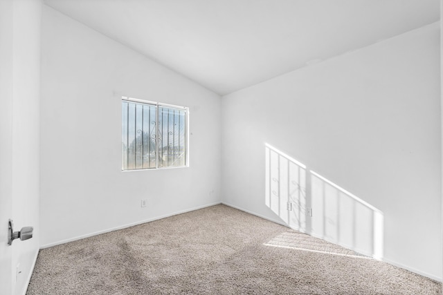 carpeted spare room with vaulted ceiling