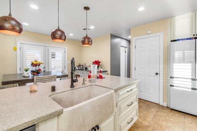 kitchen featuring light stone countertops, sink, pendant lighting, and white refrigerator