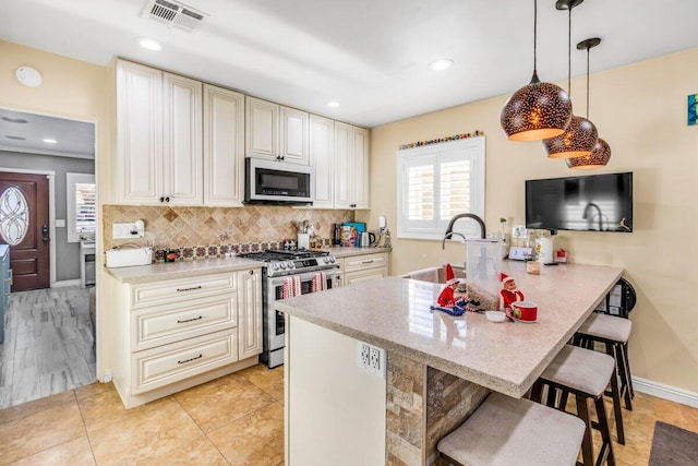 kitchen featuring stainless steel stove, decorative backsplash, decorative light fixtures, kitchen peninsula, and a breakfast bar area