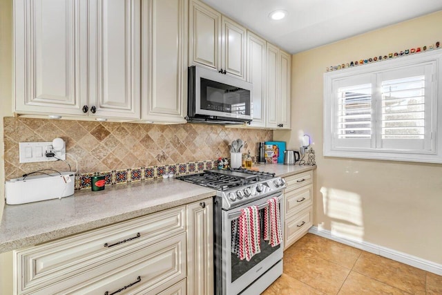 kitchen with tasteful backsplash, light tile patterned floors, cream cabinetry, and appliances with stainless steel finishes