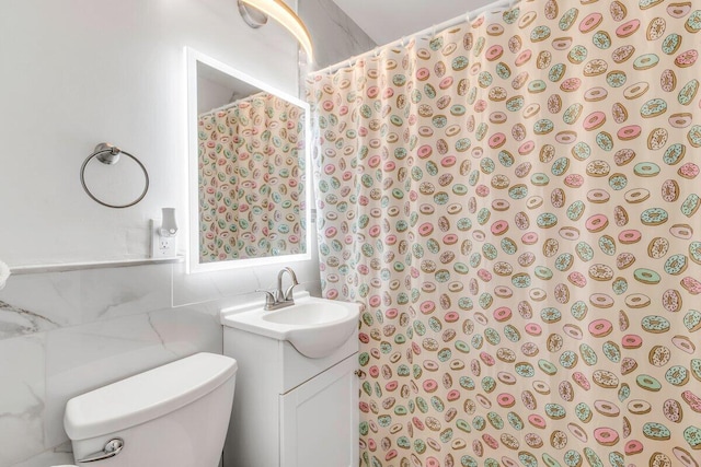 bathroom featuring tasteful backsplash, vanity, tile walls, and toilet