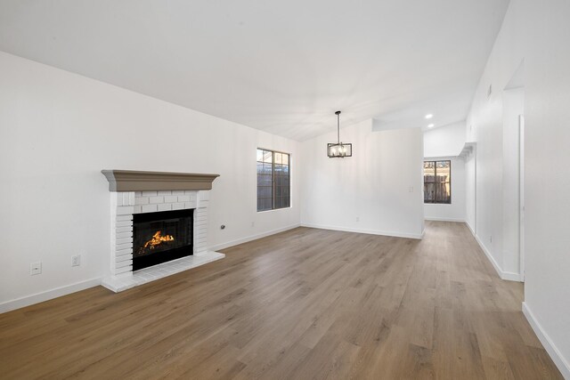 2203 Scott Ave, Palmdale, CA 93550 - unfurnished living room with a fireplace, lofted ceiling, light wood-style flooring, a chandelier, and baseboards