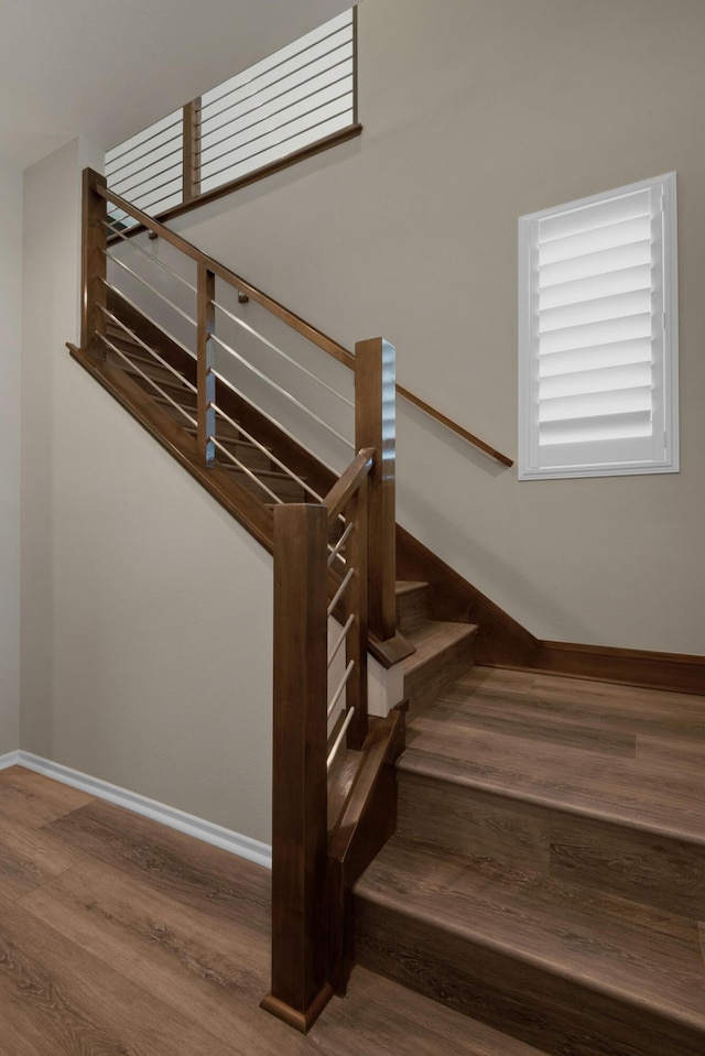 staircase featuring baseboards and wood finished floors