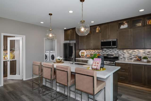 kitchen featuring stainless steel appliances, a sink, light countertops, backsplash, and washer and clothes dryer