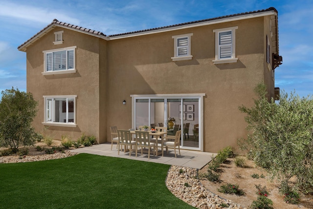 rear view of house featuring a yard, a patio, a tiled roof, and stucco siding