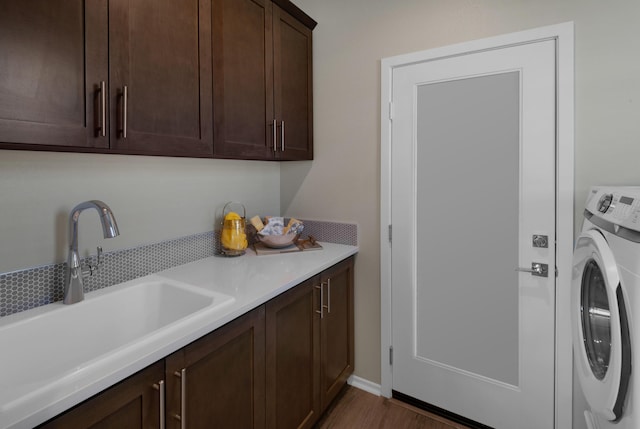 laundry room featuring wood finished floors, washer / clothes dryer, a sink, and cabinet space