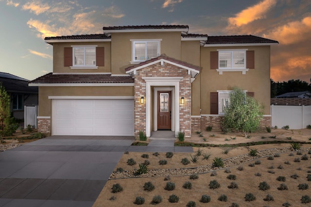 view of front of property with brick siding, driveway, an attached garage, and stucco siding