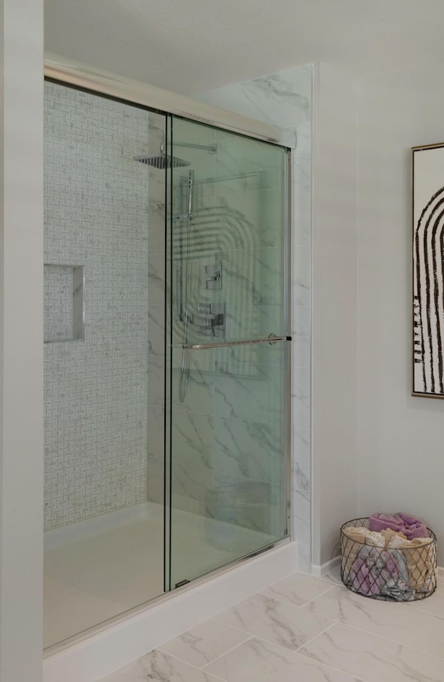 bathroom with marble finish floor and a stall shower