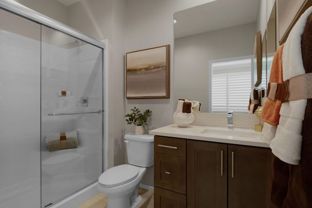 bathroom featuring vanity, a shower stall, and toilet