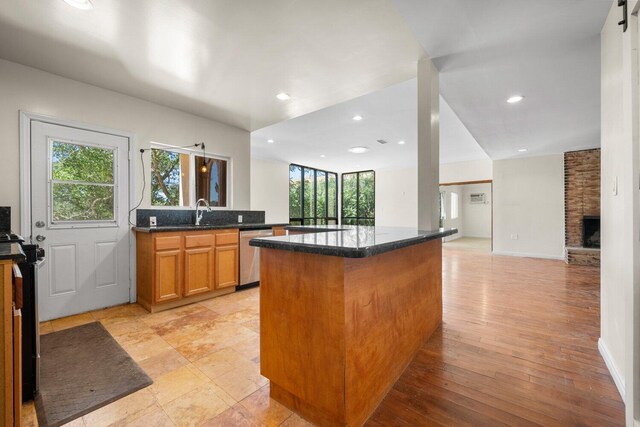 13113 Johnson Rd, Lake Hughes, CA 93532 - kitchen with dishwasher, light hardwood / wood-style flooring, a stone fireplace, and a wealth of natural light
