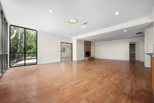 13113 Johnson Rd, Lake Hughes, CA 93532 - unfurnished living room with a wall of windows, ornamental molding, light hardwood / wood-style flooring, and a brick fireplace