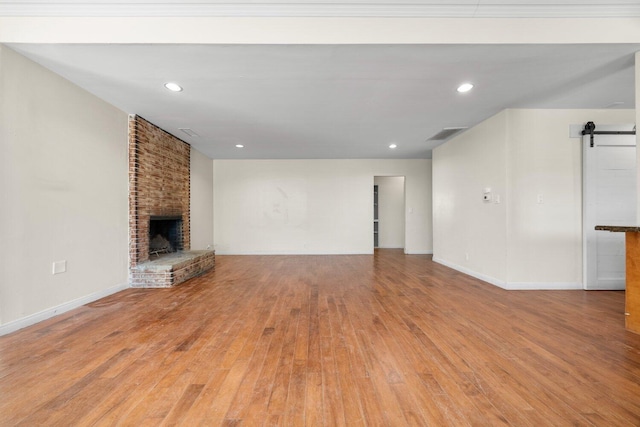 13113 Johnson Rd, Lake Hughes, CA 93532 - unfurnished living room featuring a barn door, a fireplace, and light wood-type flooring