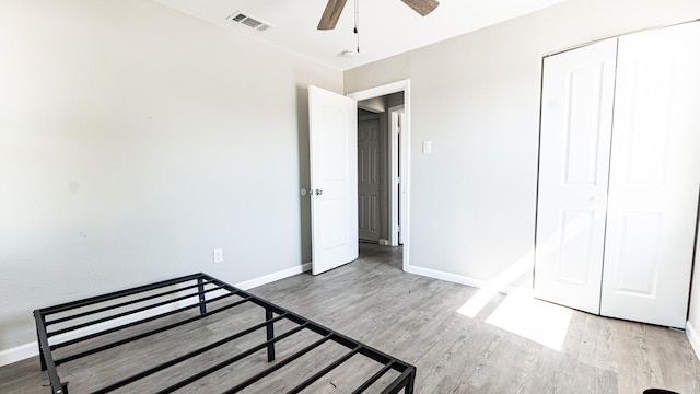 unfurnished bedroom featuring light wood-style flooring, baseboards, a ceiling fan, and a closet