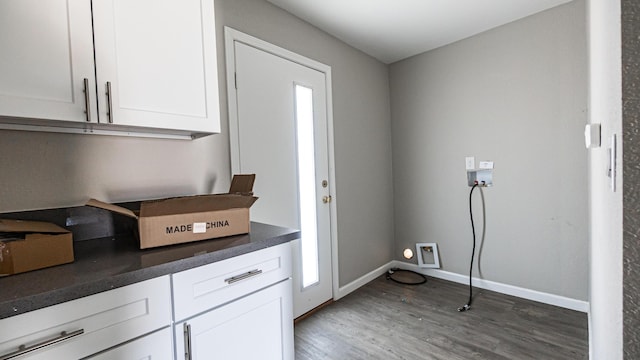 clothes washing area featuring hookup for a washing machine, wood finished floors, cabinet space, and baseboards
