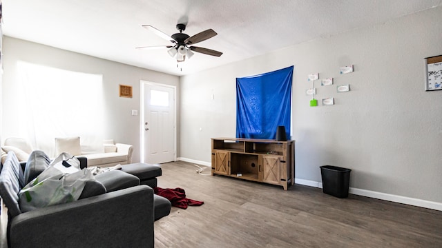 living area featuring wood finished floors, a ceiling fan, and baseboards