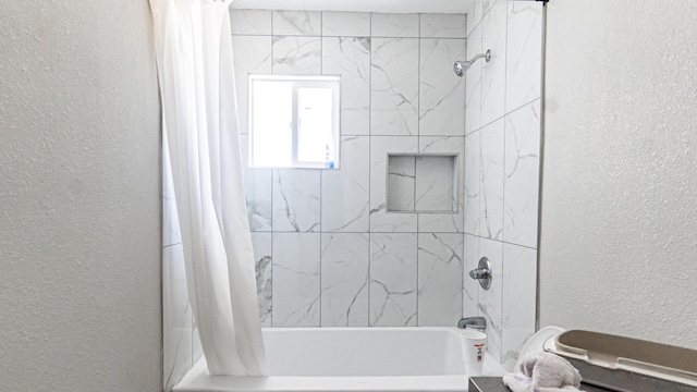 bathroom featuring a textured wall and shower / bath combination with curtain