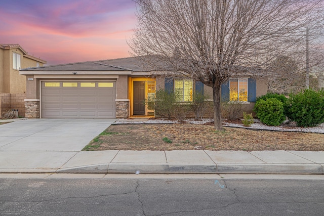 view of front facade featuring an attached garage, stone siding, concrete driveway, and stucco siding