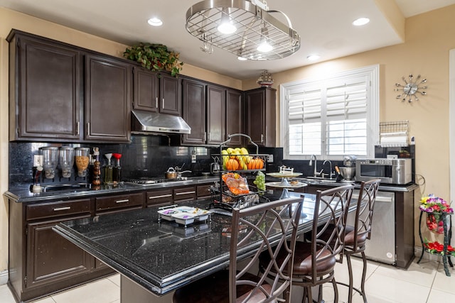 40947 Ridgegate Ln, Palmdale, CA 93551 - kitchen with under cabinet range hood, dark brown cabinets, stainless steel gas stovetop, and light tile patterned floors