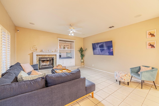 living area featuring visible vents, a ceiling fan, light tile patterned flooring, baseboards, and a tile fireplace