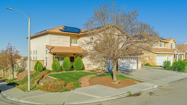 view of front of home with driveway, stucco siding, a garage, a tiled roof, and roof mounted solar panels