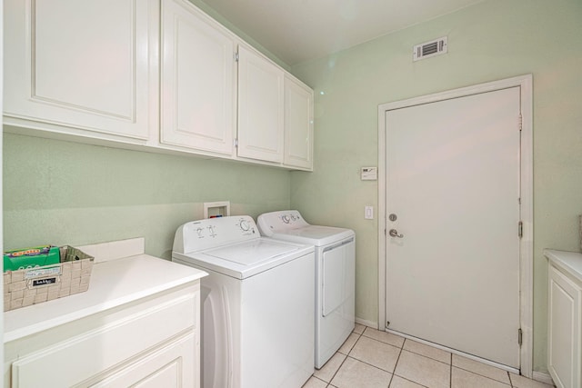 laundry room featuring light tile patterned floors, washing machine and dryer, cabinet space, and visible vents