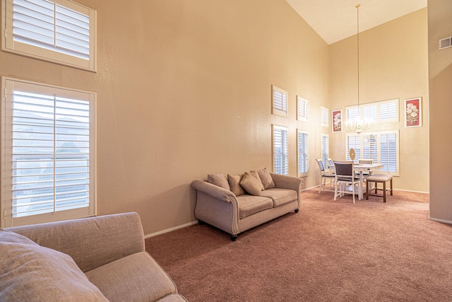 carpeted living area with a notable chandelier, visible vents, high vaulted ceiling, and baseboards