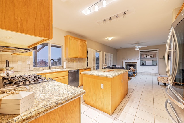 kitchen with a center island, dishwasher, a fireplace, stainless steel refrigerator, and a sink