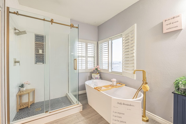 full bath featuring a soaking tub, a shower stall, baseboards, and wood finished floors